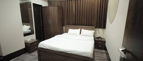 A bedroom with a bed, a wardrobe, a nightstand, a ceiling fan, and an air conditioning unit.