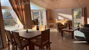 A spacious room with wooden furniture, a dining table, and a sofa.