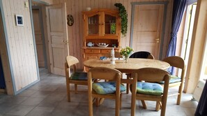 A dining area with a wooden table and chairs, a cabinet with glass doors, and a potted plant. - Ferienhaus im skandinavischen Stil (Rechlin)