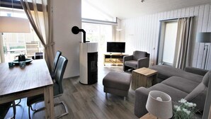 A modern living room with a wooden dining table, grey sofa, and a television. - Ferienhaus im Ferienpark Mueritz (Rechlin)