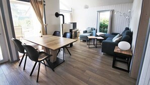 A modern living room with a wooden dining table, black chairs, a blue sofa, and a TV.