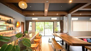 A modern interior with a wooden ceiling, a bar area with shelves, and a dining space with wooden tables and chairs. - Likha Wellness Resort (Lipa)