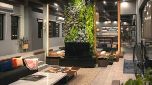 A modern lounge area with a vertical garden, comfortable seating, a flat-screen TV, and a bar area with shelves of bottles and glasses. - Likha Wellness Resort (Lipa)