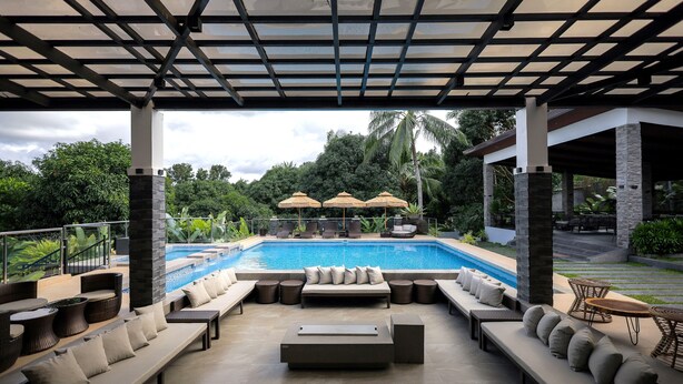 A poolside area with lounge seating, umbrellas, and a view of the pool. - Likha Wellness Resort (Lipa)