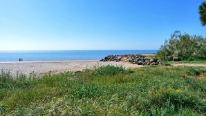Une plage avec un promontoire rocheux et une vue dégagée sur la mer.