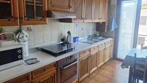 A kitchen with wooden cabinets, a stainless steel sink, a built-in oven, and a microwave. - Large and bright apartment in residential area, 6 bus stops from metro A (Roma)