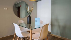 A modern dining area with a glass table, white chairs, a vase with flowers, and a "Welcome to Lima" sign.