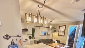 A modern kitchen with a white countertop, bar stools, and a hanging light fixture. - Small Cabin, Big Comfort. Ski-in/Ski-Out, Hike, Bike & Chill. Hot Tub & Sauna. (Kimberley)