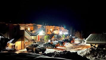 Vue nocturne d’une rue résidentielle, avec des maisons et des voitures garées.