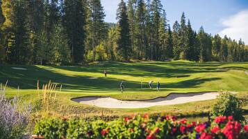 Un parcours de golf avec des bunkers de sable, un étang et des arbres denses en arrière-plan.
