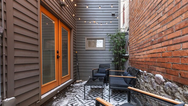 A patio with outdoor furniture, a small window, and string lights.