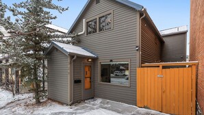 A two-story house with a gray exterior, a small attached garage, and a wooden gate.