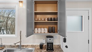 A kitchen with a built-in cabinet, a coffee maker, and a window with a view of trees.