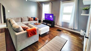 Una sala de estar moderna con un sofá modular, un televisor de pantalla plana, un ventilador de techo y una planta en maceta.