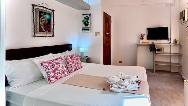 Una habitación de hotel con cama, televisor, escritorio y puerta de baño.