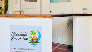 Zona de recepción con un cartel del Moonlight Breeze Inn, que incluye números de contacto e iconos de redes sociales.