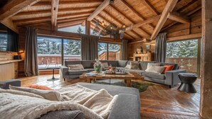 A cozy cabin interior with a wooden ceiling, large windows, a grey sofa set, and a wooden coffee table. - Fantastique mansarde appartement (Zermatt)