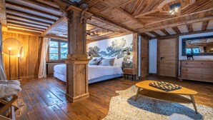 A cozy bedroom with a large bed, wooden beams, a fireplace, and a chessboard on a rug. - Fantastique mansarde appartement (Zermatt)