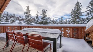 A wooden deck with a table and chairs, surrounded by snow-covered trees and a cloudy sky. - Fantastique mansarde appartement (Zermatt)