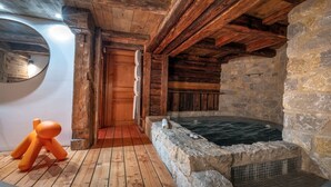 A rustic cabin interior with a stone wall, wooden beams, and a wooden floor. - Fantastique mansarde appartement (Zermatt)
