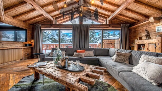 A cozy log cabin interior with a wooden ceiling, a large sofa, a coffee table, and a view of snowy mountains through large windows. - Fantastique mansarde appartement (Zermatt)