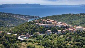 A coastal town with a prominent church tower, surrounded by lush greenery and a clear view of the sea.