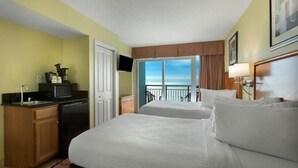 Une chambre d’hôtel avec deux lits, une kitchenette, une télévision et un balcon avec vue.