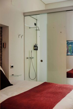Relax in a stylish room with a large bed, glass-enclosed shower, and convenient bedside table.