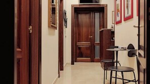 A hallway with a wooden door, a small table with two chairs, and a mounted television. - Da Celeste (Naples)