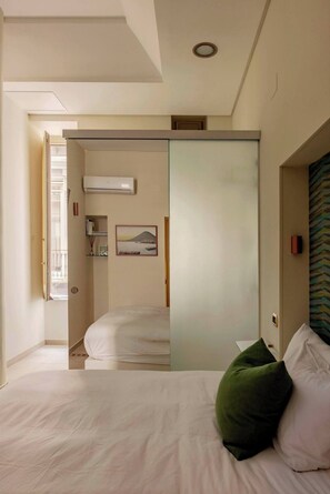 Relax in a serene space with a large bed, sliding door to the bathroom, and a framed picture above.