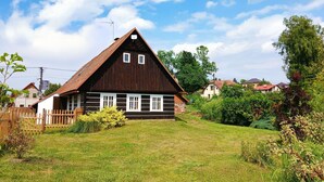 Ein traditionelles Holzhaus mit Satteldach, Holzzaun und einem Rasen.