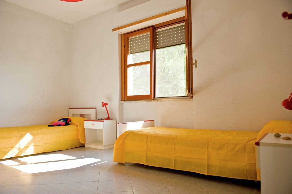 A room with two beds, a window, a desk, and a chair.