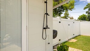 A residential outdoor area with a white exterior wall, a white fence, and a green lawn. - Luxury Pool Retreat near Siesta Key  (Sarasota)