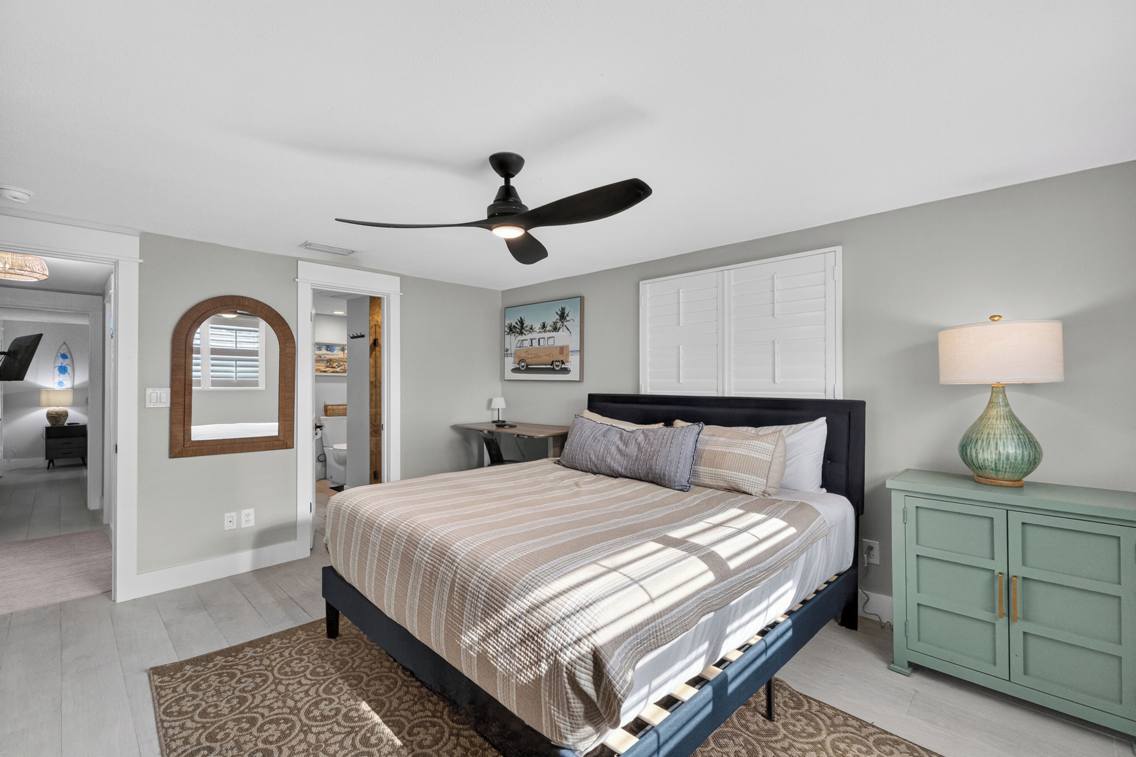 A bedroom with a bed, a ceiling fan, a nightstand, a lamp, and a cabinet.