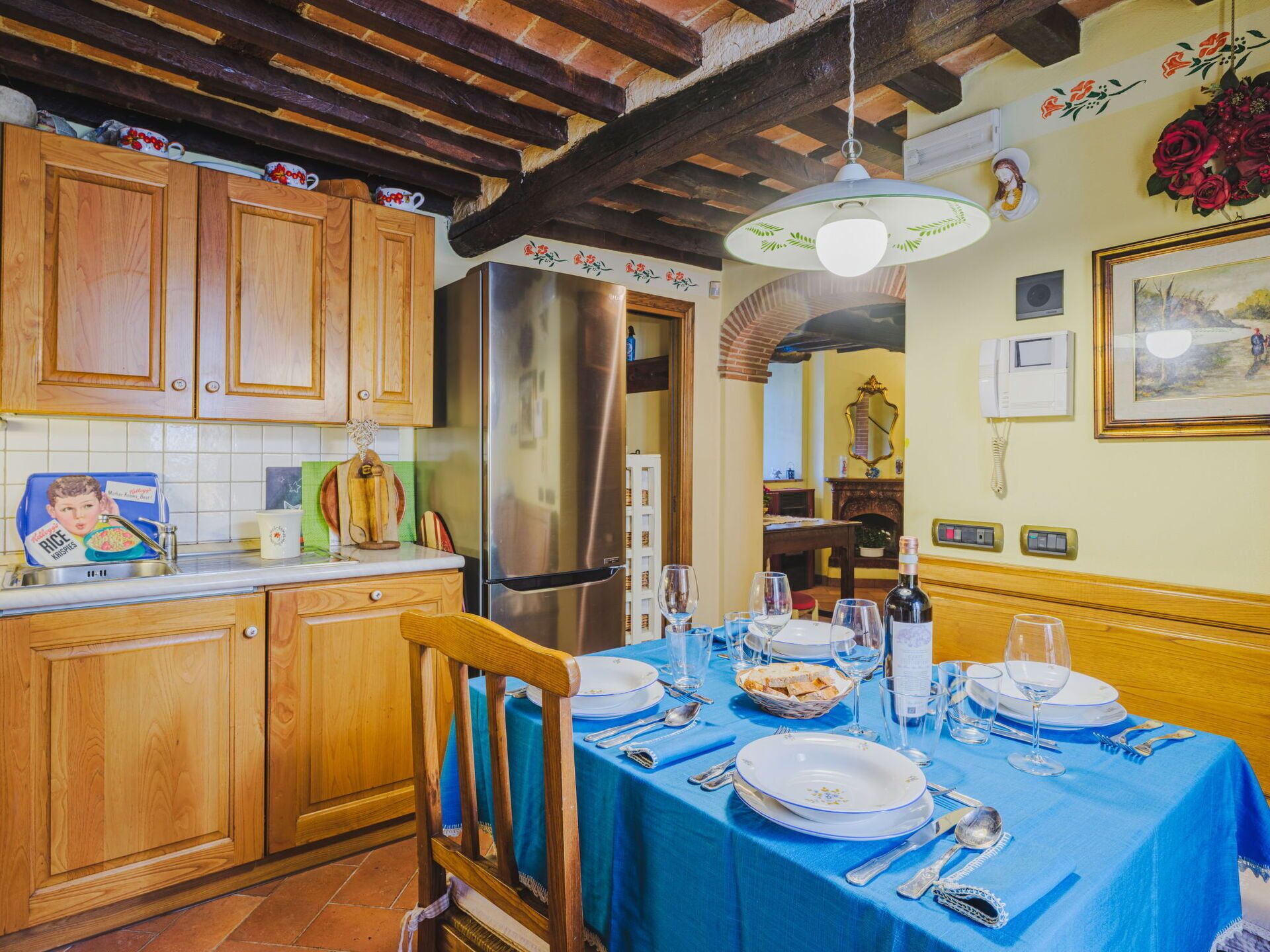 A kitchen with wooden cabinets, a stainless steel refrigerator, and a dining table set for a meal.