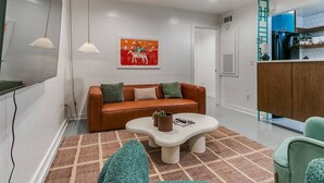 Un salon moderne avec un canapé en cuir marron, une table basse blanche et un tapis coloré.
