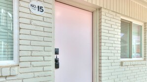 Une porte blanche dotée d’un clavier pour l’ouverture, une plaque d’immatriculation indiquant le numéro « 15 », et une fenêtre située à droite.