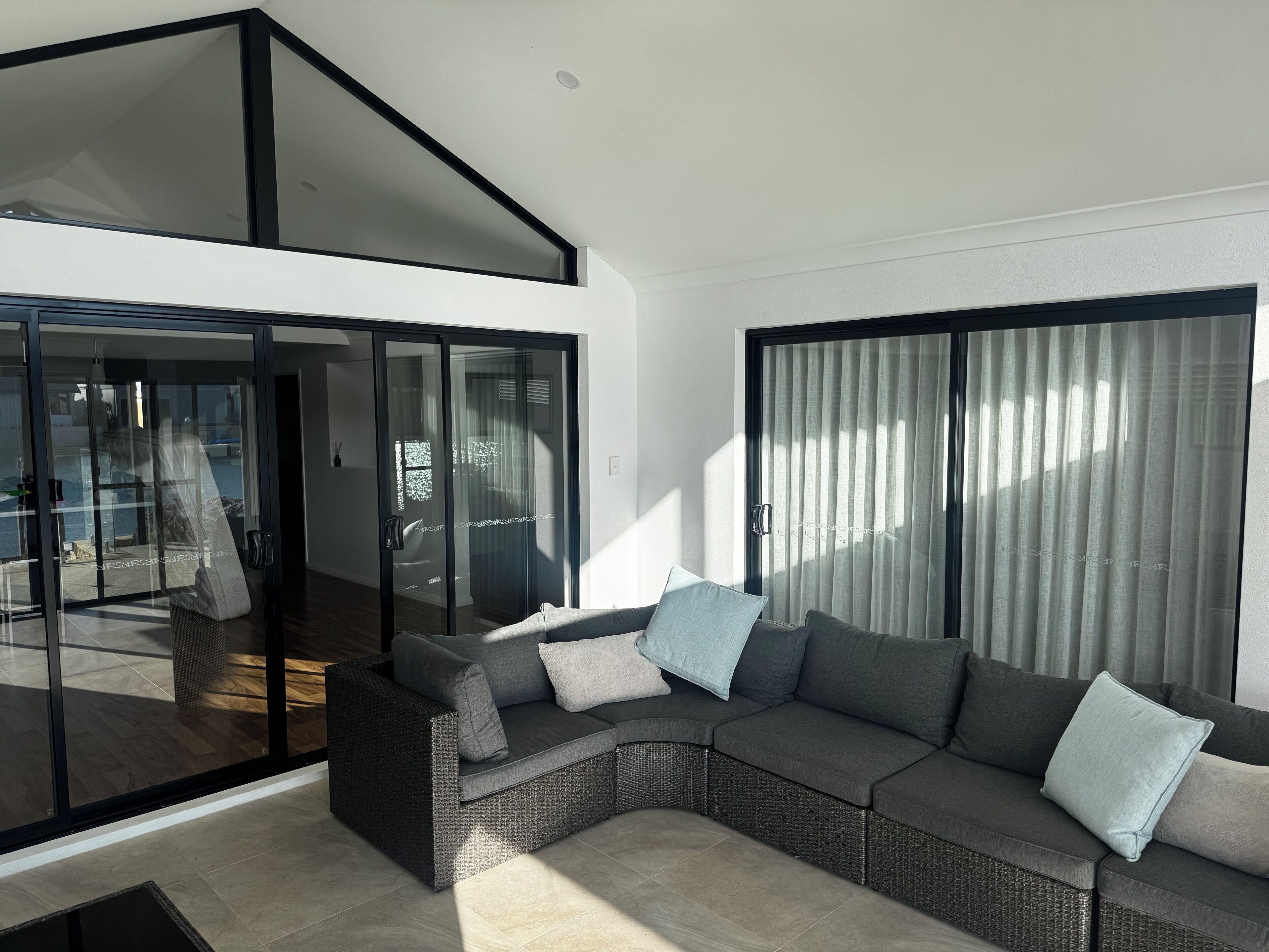 A modern living room with a sectional sofa, large sliding glass doors, and a view of the outdoor area.
