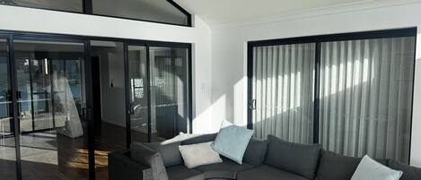 A modern living room with a sectional sofa, large sliding glass doors, and a view of the outdoor area.