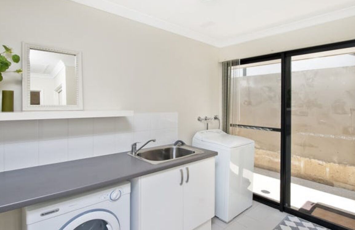 A compact kitchen with a sink, washing machine, and a small countertop.