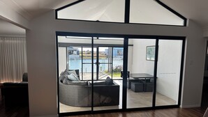 A spacious living area with a large sliding glass door leading to an outdoor patio. - Canal Waters relax and enjoy even bring the boat to the back door (Geographe)