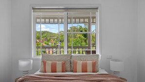 A bedroom with a large window, a bed with striped pillows, and two bedside lamps. - "Salt & Serenity" – close to Beach & Shops (Terrigal)
