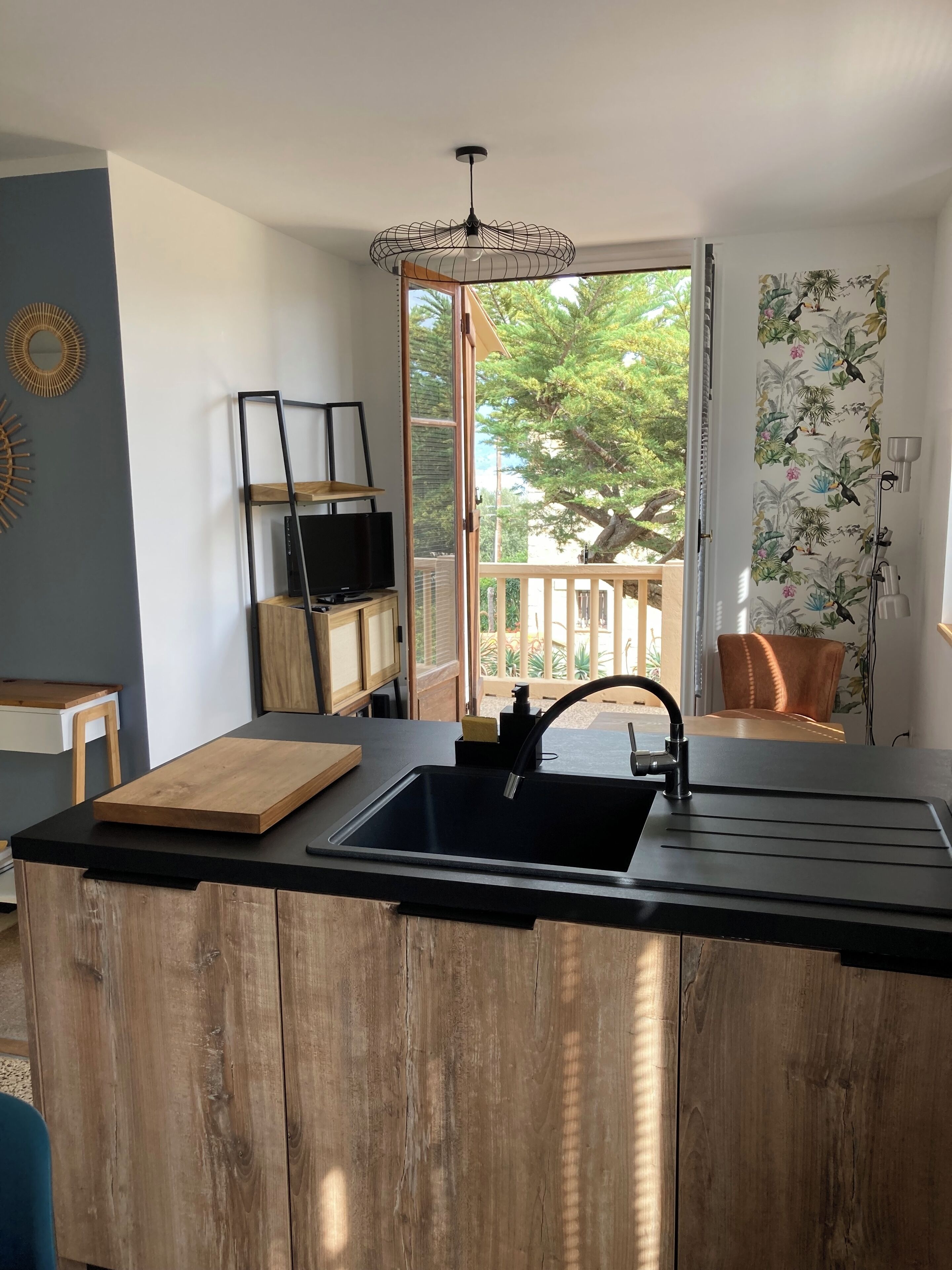 A modern kitchen with a large island, a built-in sink, and a view of the outdoors.