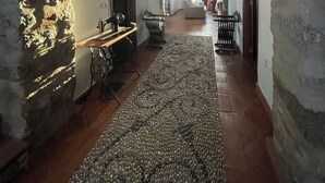 Un couloir orné d’arches en briques, une cheminée rustique, un tapis tissé et un coin repas avec une table et des chaises.