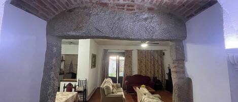 Una sala de estar con un sofá, una mesa de comedor con sillas y una cocina visible a través de un arco.