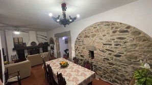 Un coin repas agrémenté d’un mur en pierre, d’un lustre et d’une table dressée pour quatre personnes.