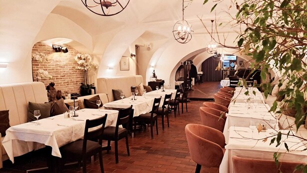 Een restaurant met lange tafels, gewelfde plafonds en hangende kroonluchters.