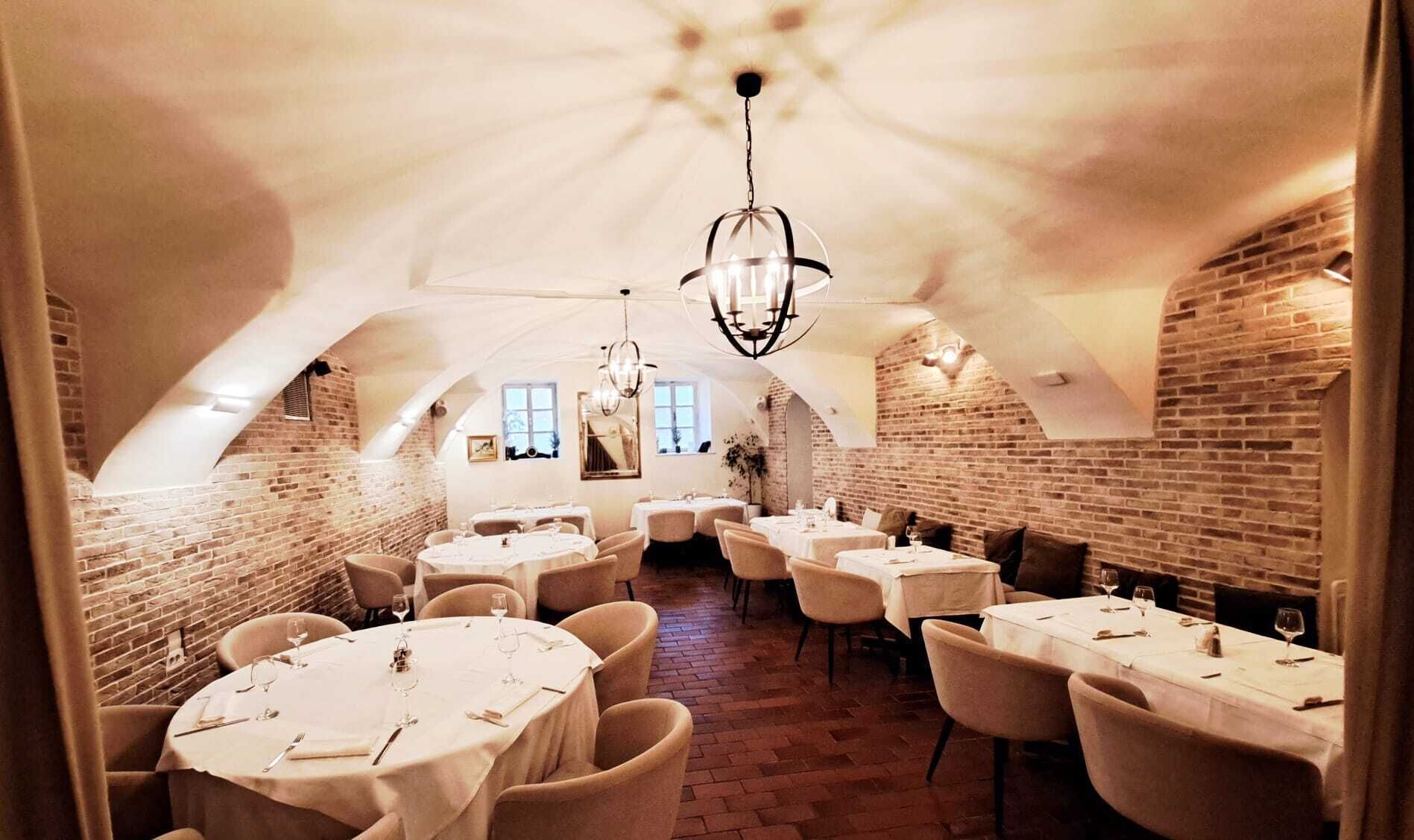 An interior with round tables, chairs, and a brick wall.