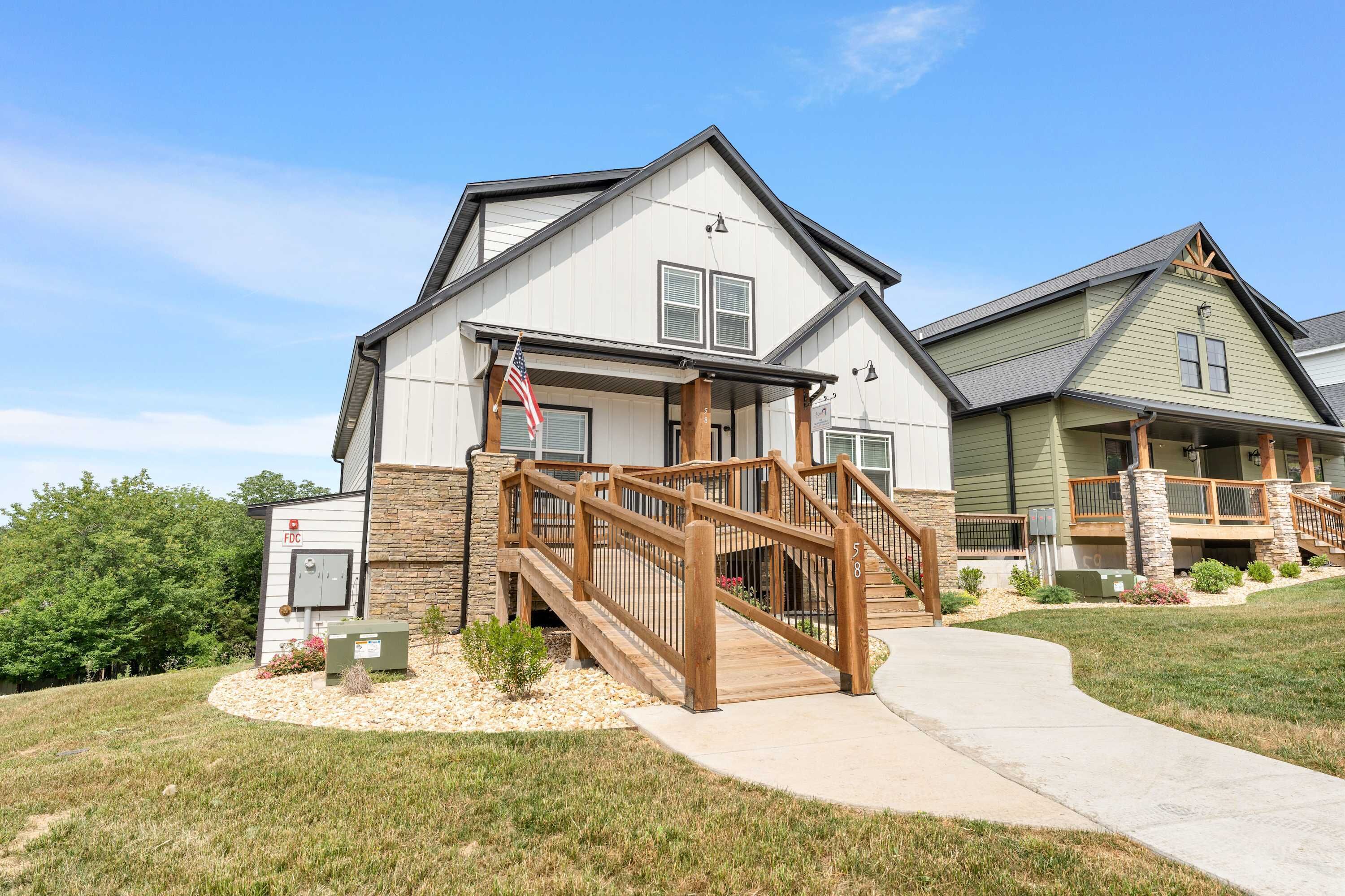 A two-story house with a wooden deck and stairs leading to the front door.