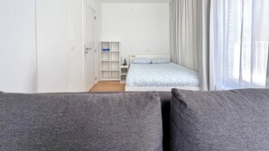 Quarto com cama, guarda-roupa, mesa de cabeceira e janela com cortinas.